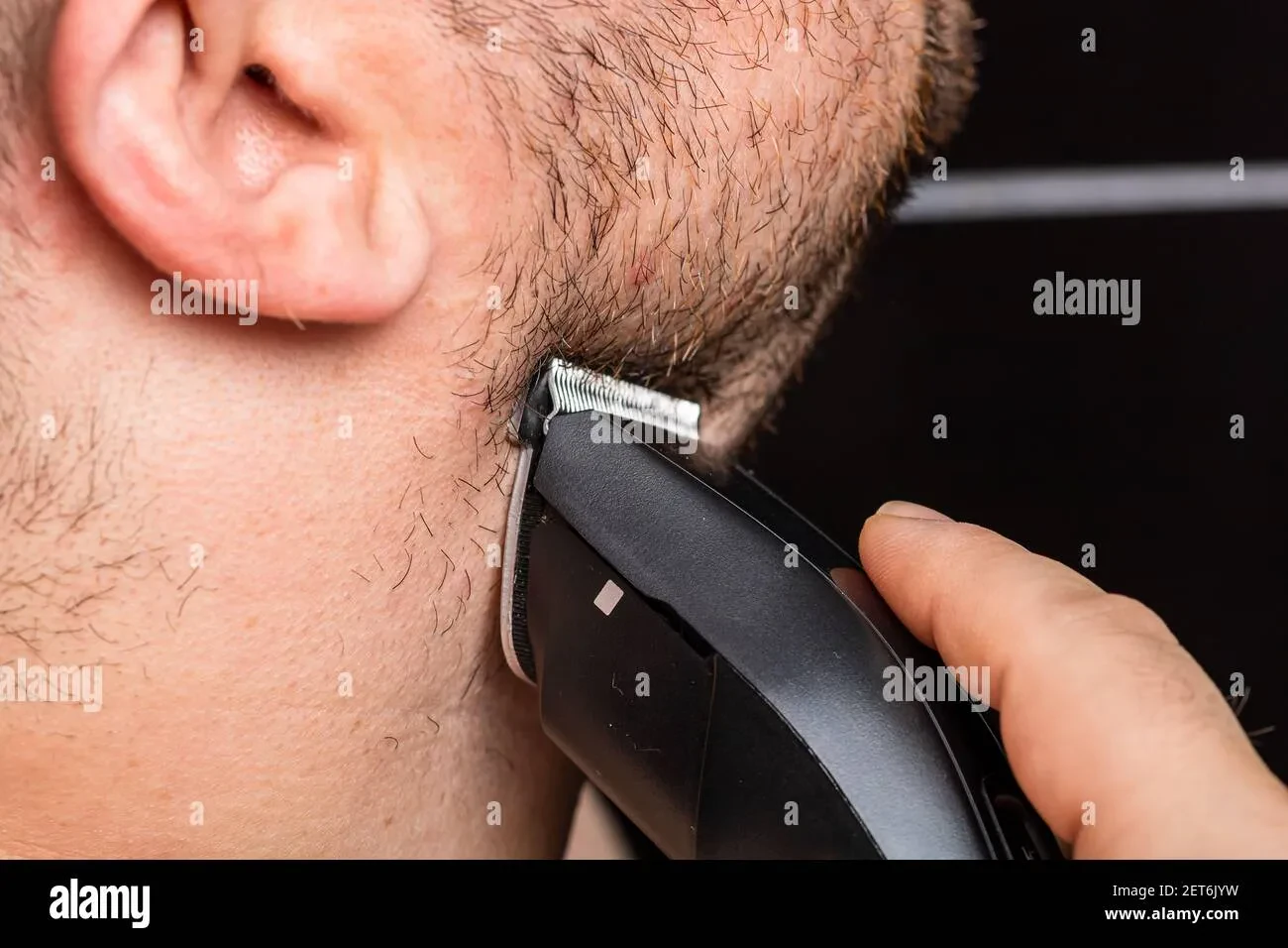 man trimming his beard with clippers